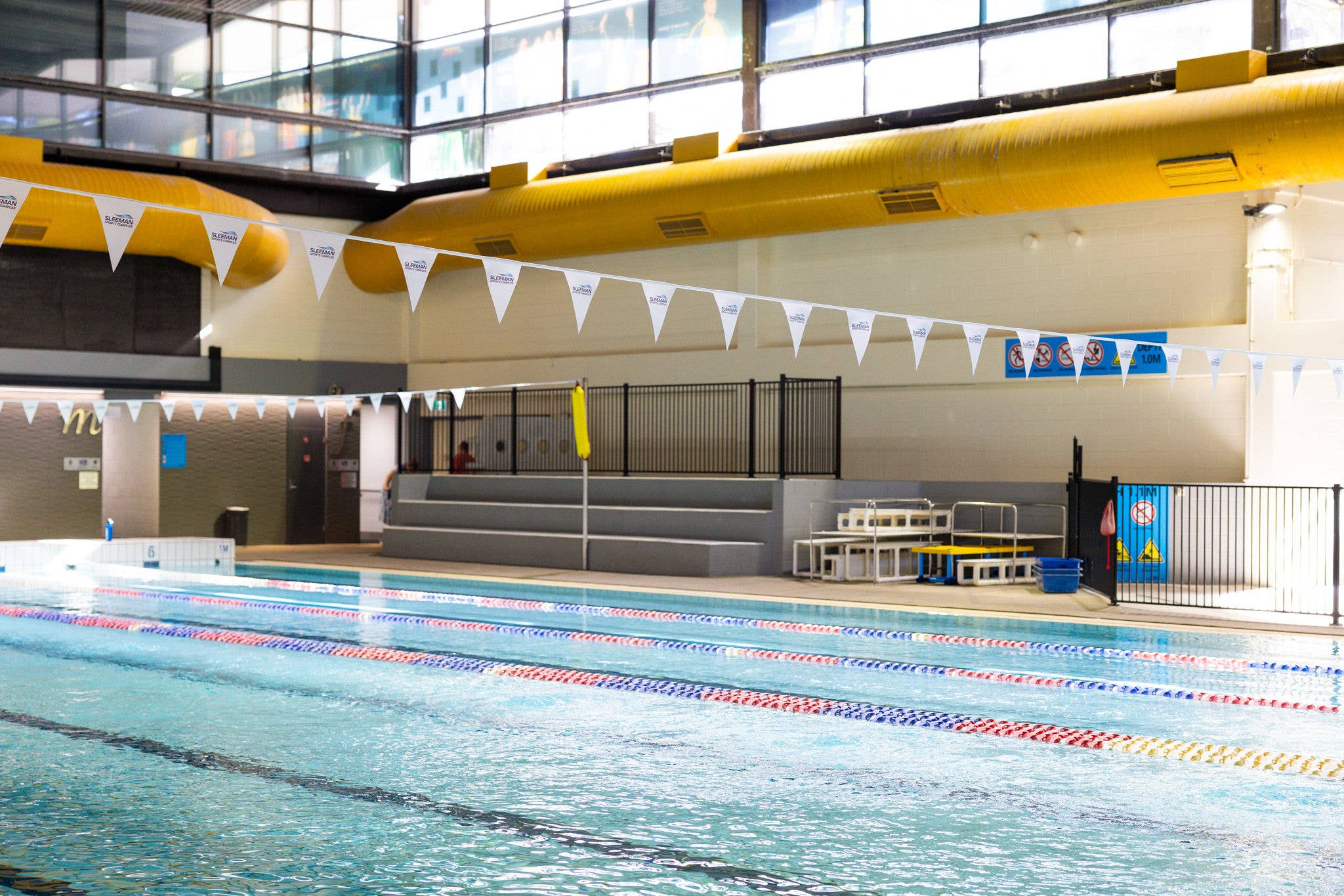 A pool with people in it and a colourful waterslide in the background