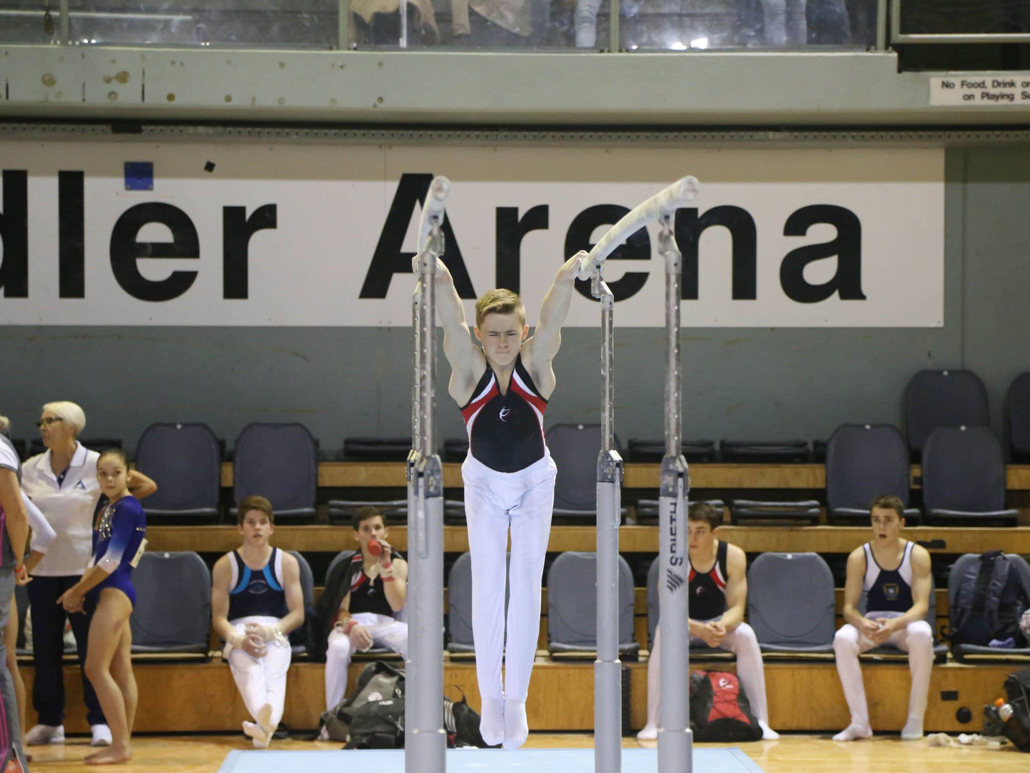 A male gymnast swings on the parallel bars