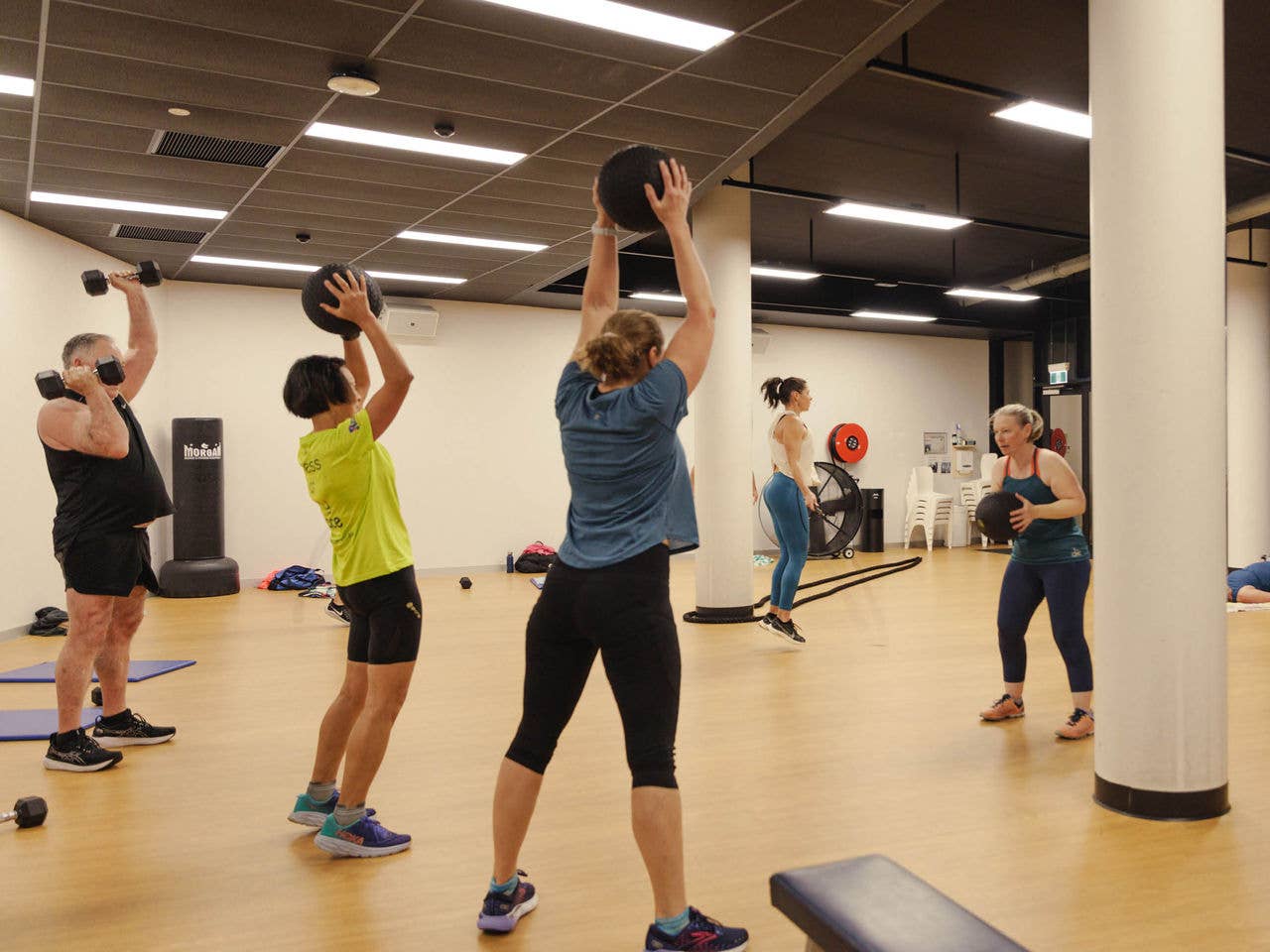 A cardio class holds balls above their heads