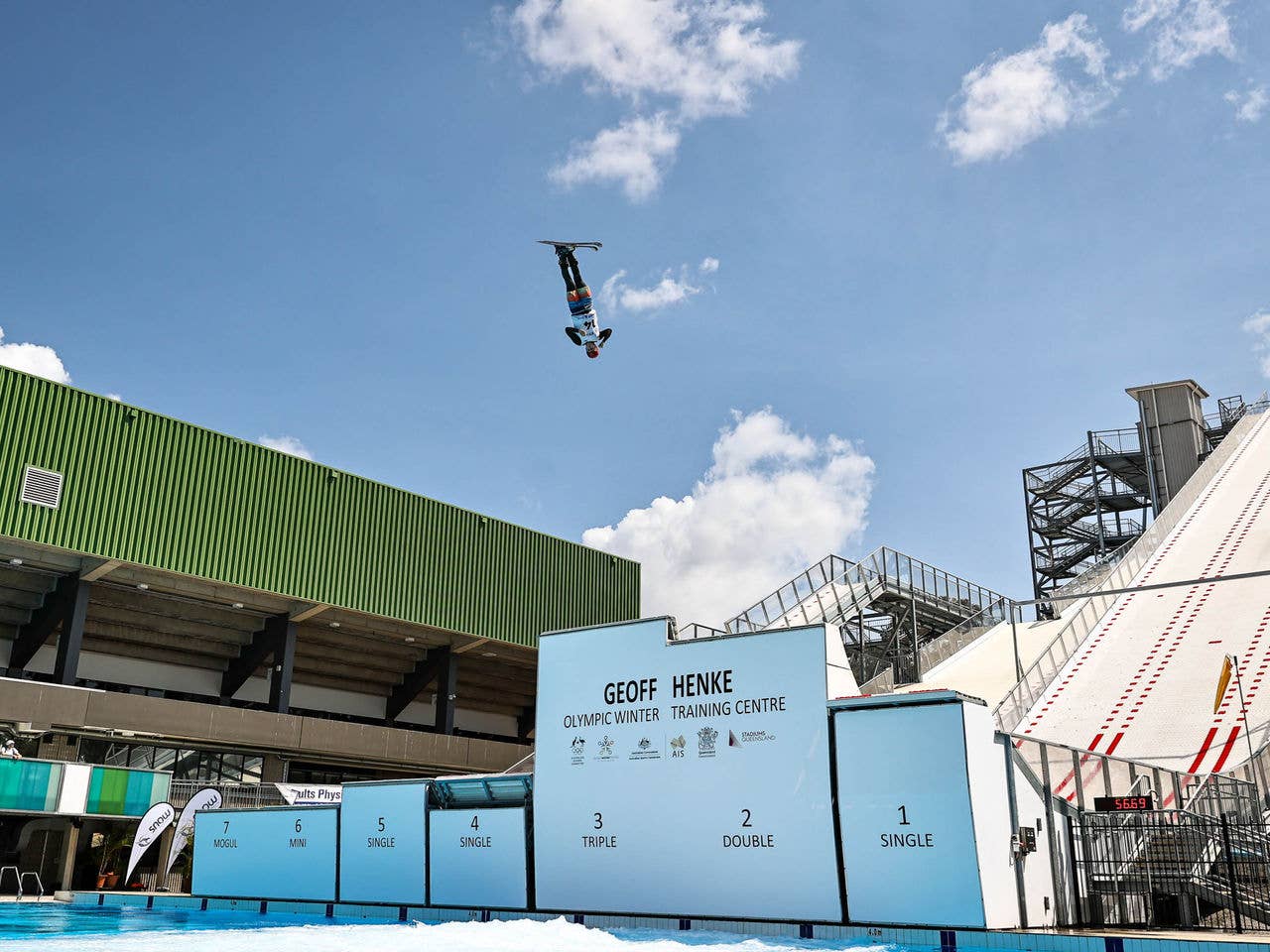 A ski jumper is mid air in front of multiple ski jumps of different heights