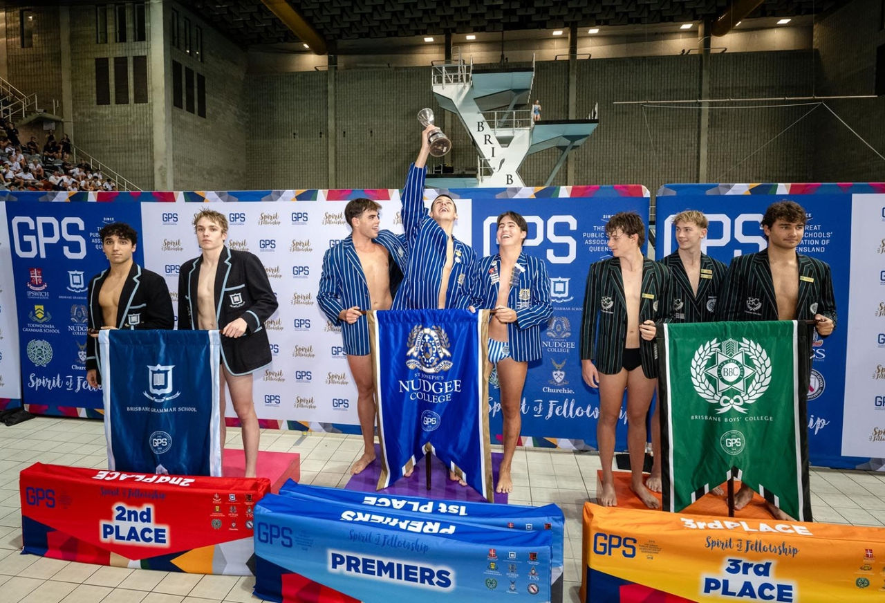 Swimmers holding trophy on podium